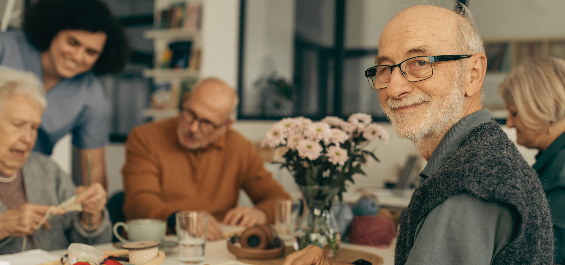 Older friends gathered around a table with flowers