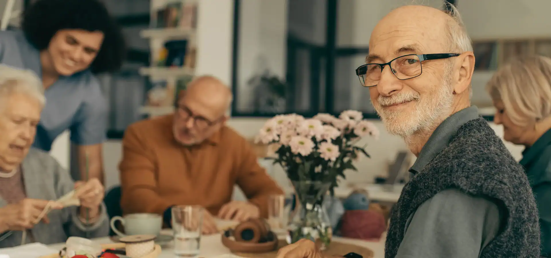 Older friends gathered around a table with flowers